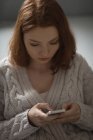 Молодая женщина пользуется мобильным телефоном дома — стоковое фото