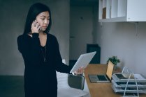 Жінка-виконавча розмова на мобільному телефоні, тримаючи цифровий планшет в офісі — стокове фото