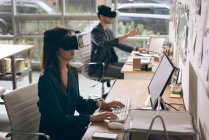Керівники робочих на ноутбуці при використанні віртуальної реальності гарнітуру в офісі — стокове фото