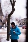 Человек, использующий мобильный телефон в городе зимой — стоковое фото