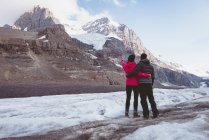 Couple standing together with arm around near mountain — Stock Photo