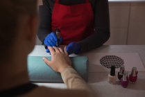 Esteticista dando tratamiento de manicura a cliente femenino en salón - foto de stock