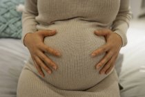 Mittelteil einer schwangeren Frau, die ihren Bauch im Geschäft berührt — Stockfoto