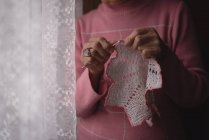 Sección media de la mujer mayor tejiendo lana en casa - foto de stock
