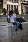 Молодой человек использует мобильный телефон на городской улице — стоковое фото