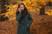 Donna che parla al telefono cellulare nel parco durante l'autunno — Foto stock