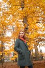 Frau steht im Herbst mit den Händen in der Tasche im Park — Stockfoto