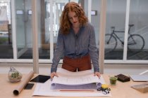 Female graphic designer working on blueprint in office — Stock Photo