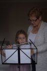 Fille jouer de la flûte avec sa grand-mère dans le salon à la maison — Photo de stock