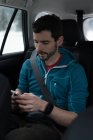 Jeune homme utilisant un téléphone portable dans une voiture — Photo de stock