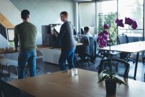 Colegas de negócios interagindo uns com os outros enquanto trabalham no escritório — Fotografia de Stock
