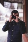 Uomo cliccando foto con fotocamera digitale fuori dal negozio — Foto stock