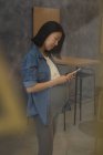Беременная деловая женщина с помощью мобильного телефона в офисе — стоковое фото