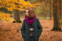 Mulher de pé com as mãos no bolso no parque durante o outono — Fotografia de Stock