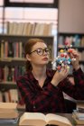 Молода жінка аналізує модель молекули в бібліотеці — стокове фото