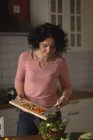 Mulher preparando salada de legumes na cozinha em casa — Fotografia de Stock