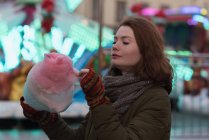 Mujer con ropa de invierno con hilo de caramelo en el parque de atracciones - foto de stock