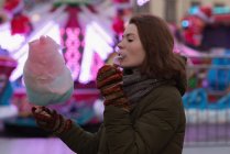 Mulher em roupas de inverno com fio dental de doces no parque de diversões — Fotografia de Stock