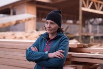Thoughtful woman standing with arms crossed against wooden plank — Stock Photo