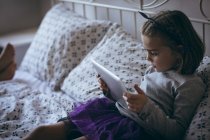 Menina usando tablet digital na cama no quarto — Fotografia de Stock