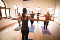 Female yoga trainer training yoga exercise to group of people in fitness club — Stock Photo