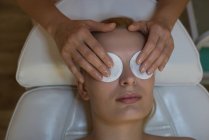 Косметолог розміщує косметичні маски на жіночих очах клієнтів у вітальні — стокове фото