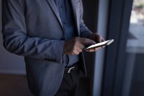 Sección media del hombre de negocios usando un teléfono inteligente en la habitación de hotel - foto de stock