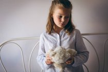 Niedliches Mädchen hält Teddybär im Schlafzimmer — Stockfoto