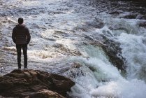 Rückansicht eines Mannes, der in der Nähe eines Wasserfalls steht — Stockfoto
