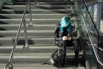 Стильна жінка використовує мобільний телефон на сходах — стокове фото