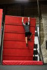 Hombre practicando escalada en roca en una pared en un gimnasio - foto de stock