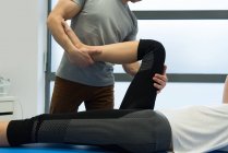 Физиотерапевт, делающий массаж ног женщине в клинике — стоковое фото