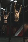 Мускулистая пара, тренирующаяся подтягиваться в баре в тренажерном зале — стоковое фото
