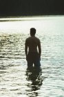 Vista trasera del hombre reflexivo de pie en un lago - foto de stock