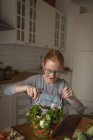 Menina preparando salada de legumes na cozinha em casa — Fotografia de Stock