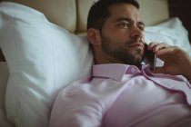 Бизнесмен разговаривает по мобильному телефону в гостиничном номере — стоковое фото