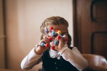 Дівчина дивиться через модель молекул вдома — стокове фото