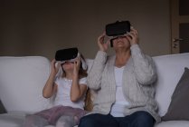 Бабушка и внучка используют гарнитуру виртуальной реальности дома — стоковое фото