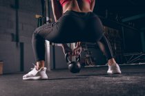 Visão traseira da mulher em forma exercitando com kettlebell no ginásio — Fotografia de Stock