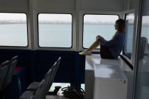 Продумана жінка сидить біля вікна в круїзному кораблі — стокове фото