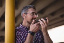 Sonriente hombre hablando en el teléfono móvil mientras se apoya en el poste - foto de stock