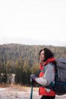 Thoughtful woman standing with backpack and hiking pole during winter — Stock Photo