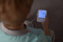 Mulher sênior verificando a pressão arterial em um monitor em casa — Fotografia de Stock