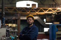 Porträt eines selbstbewussten Technikers, der mit verschränkten Armen in der Metallindustrie steht — Stockfoto