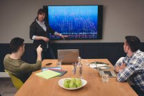 Ділова жінка дає презентацію колегам в кімнаті для переговорів в офісі — стокове фото
