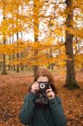 Жінка фотографується з старовинною камерою в парку восени — стокове фото