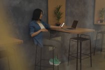 Беременная деловая женщина с помощью мобильного телефона на рабочем столе в офисе — стоковое фото