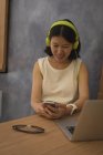 Вагітна бізнес-леді слухає музику на мобільному телефоні за столом в офісі — стокове фото