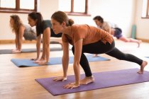 Grupo de pessoas que realizam exercícios de ioga em conjunto no clube de fitness — Fotografia de Stock
