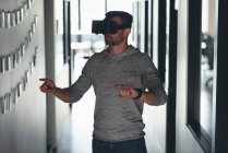 Homem de negócios usando headset realidade virtual no corredor no escritório — Fotografia de Stock
